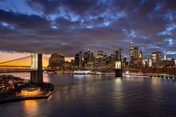Fototapeta na wymiar Brooklyn Bridge and waterfront with the East River. Dumbo, and Lower Manhattan illuminated skyscrapers at twilight, New York City