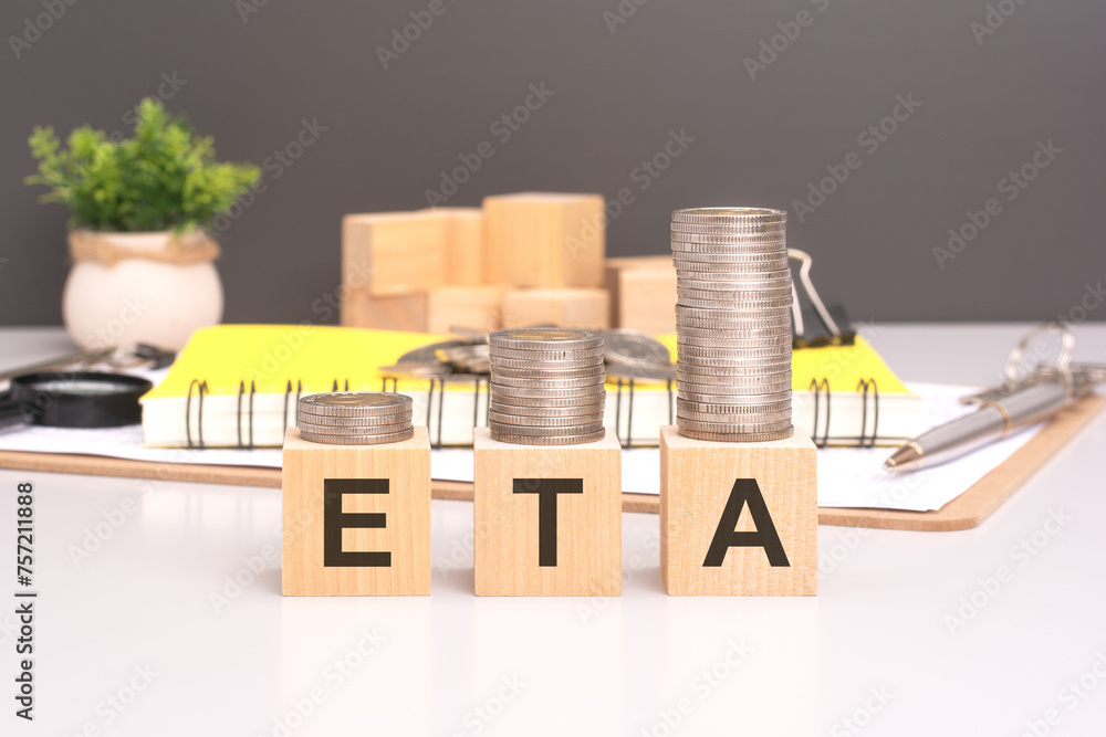 Aufkleber eta text in wooden blocks with coins stacked in increasing stacks. estimated time of arrival concept