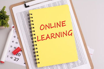 yellow notebook with 'ONLINE LEARNING' text on a grey background signifies a focus on education, skill development, and digital learning in the financial realm.