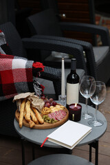 rest and relaxation. red wine, glasses, book, candles and snacks are on the table. romantic dinner on the terrace. aesthetic photo. wooden board with grapes, cheese, sausage, olives and grisini