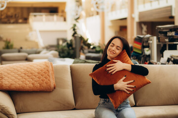 Portrait of young woman choosing pillow at store of household goods