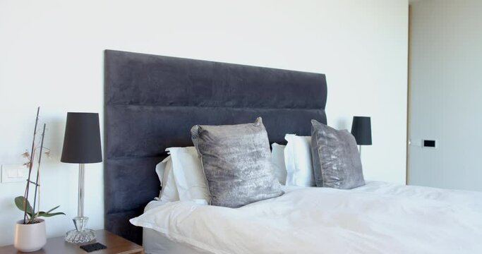 A modern bedroom features a large grey headboard and matching lamps with copy space