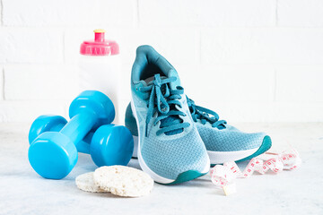 Fitness background on white. Sneakers, dumbbells, towel and diet food. Fitness, workout and diet...