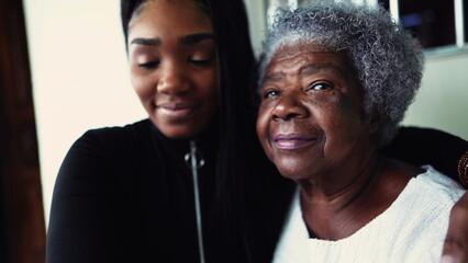 African American granddaughter hugging elderly 80s grandmother showing support and help for inter-generational family member. Family unity and love during old age - obrazy, fototapety, plakaty