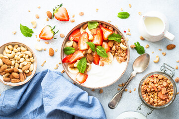 Yogurt with granola, nuts and strawberries on white. Healthy snack or breakfast, fruit salad. Top view with copy space.