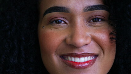 One joyful brazilian black latin woman macro close-up face smiling at camera. Curly hair adult girl...