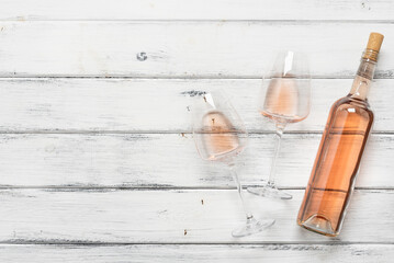 Bottle and two glasses with rose wine flat lay on a white wooden background. Top view, copy space. Pink wine. - 757228626