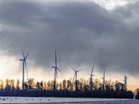 Wind turbines standing tall as the day transitions to twilight