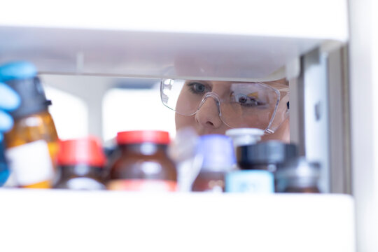 Curious scientist gazing at chemical samples in a laboratory fridge