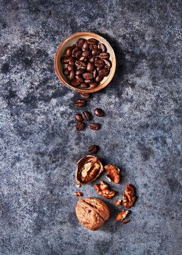 Spilled coffee beans and walnuts on a textured surface