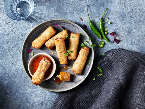 Savory spring rolls served on a stone plate with dipping sauce