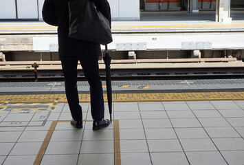朝の通勤時間のJR名古屋駅のホームで電車待ちの一人のサラリーマンの姿