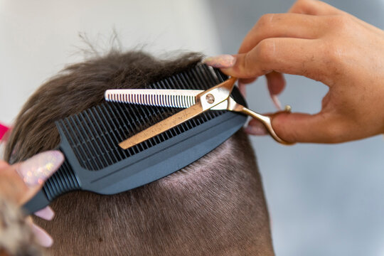 Stylist giving a precise haircut with focus on the details.