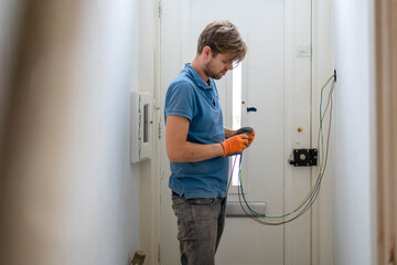 A focused technician working on electrical wiring at home.