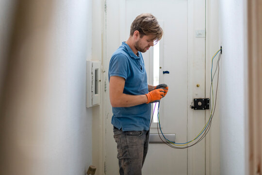A focused technician working on electrical wiring at home.