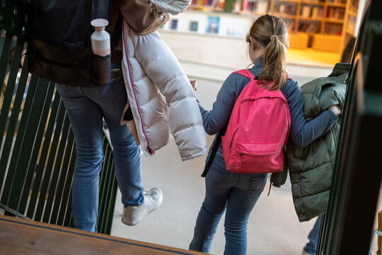 A mother and daughter holding hands while walking up the stairs, ready for a new day of learning. - Powered by Adobe