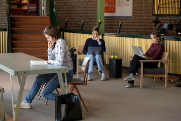 Three students focused on their work in a modern study hall.