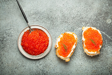 Small metal plate with red salmon caviar and two caviar toasts canape on grey concrete background, festive luxury delicacy and appetizer. - 757234241