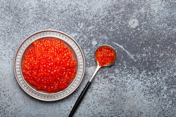 Small metal plate with red salmon caviar and a spoon top view on grey concrete background, festive luxury delicacy and appetizer. - 757234429