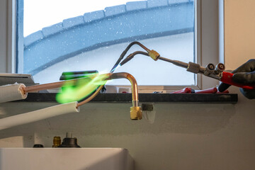 Sparks fly as a professional works on plumbing under a bright window.