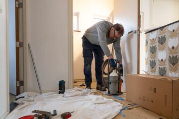 A focused handyman installing flooring in a bright room.