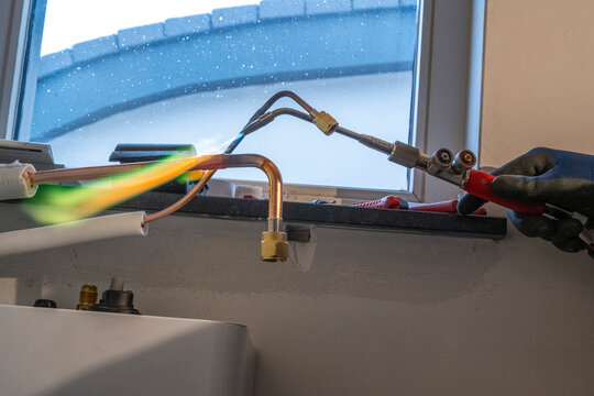 A professional at work using a blowtorch for pipe soldering