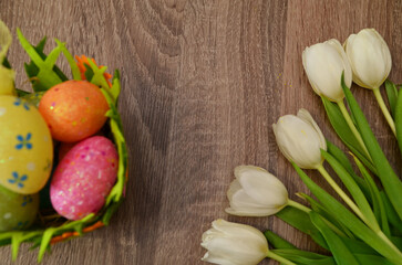 Easter concept. easter eggs in bowl ceramic easter bunnies yellow and pink tulips on isolated light beige background