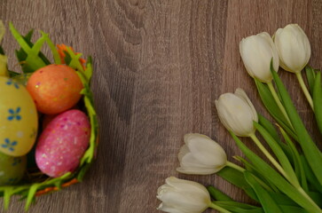 Easter concept. easter eggs in bowl ceramic easter bunnies yellow and pink tulips on isolated light beige background