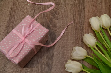 white tulips on wooden background gift in a pink box with a pink ribbon. Mothers day, Valentines Day, Birthday celebration concept. Greeting card. Copy space for text, top view