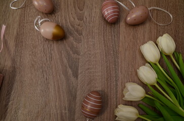 Easter concept. easter eggs in bowl ceramic easter bunnies yellow and pink tulips on isolated light beige background