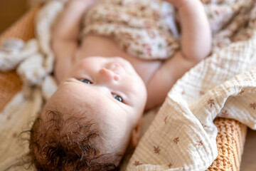 Baby gazing curiously while lying down surrounded by cozy blankets.