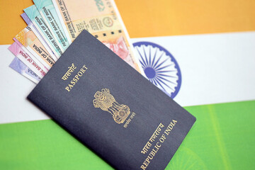 Blue Indian passport and Indian rupees money bills on flag background close up. Tourism and citizenship concept