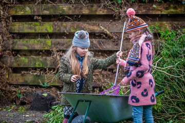 Two children gardening with a wheelbarrow