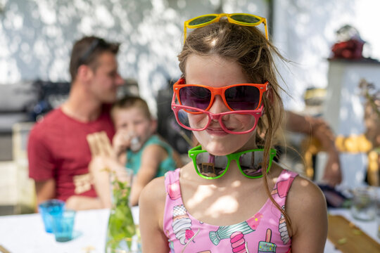 Girl wearing multiple pairs of colorful sunglasses