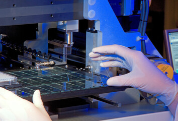 A technician carefully handles delicate components in a high-tech manufacturing setting