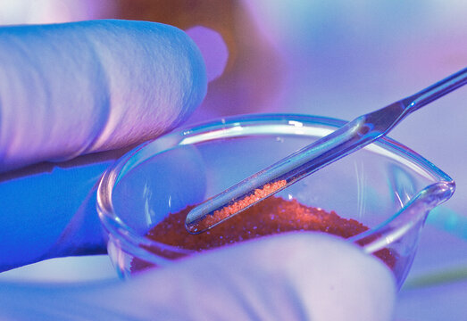 Close-up of a laboratory scene with a scientist manipulating substances with tweezers and a petri dish