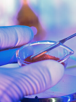 Scientist's hand manipulating samples in a petri dish under neon light