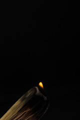 Palo santo burning with flame and smoke with dark background in vertical and copy paste Bursera graveolens