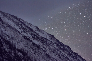 Highland mountain covered in snow under starry night sky atmosphere