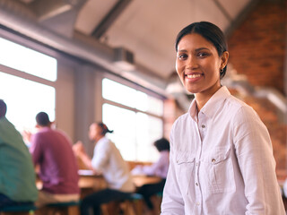 Young Smiling Businesswoman Working In Open Plan Office With Colleagues In Background - 757238639