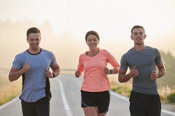 A group of friends, athletes, and joggers embrace the early morning hours as they run through the...