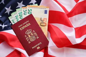 Fototapeta na wymiar Red Spanish passport of European Union and money on United States national flag background close up. Tourism and diplomacy concept