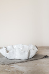 white ceramic plate with an uneven edge on a linen napkin. Side view. Mockup.