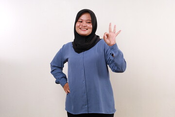 Asian muslim woman standing while making okay hand gesture