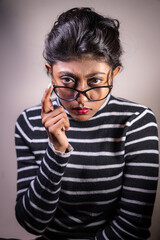 A woman with glasses and a striped shirt is posing for a photo. She is wearing a red lipstick and...