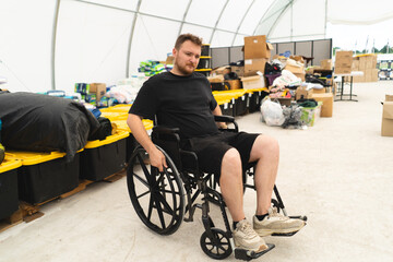 A veteran disabled man in a wheelchair helps in a humanitarian unit. Support of war victims....