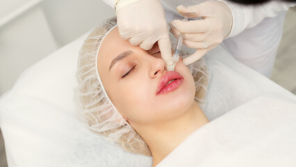 Injection procedure for lip augmentation, close-up. The cosmetologist slowly and carefully injects...