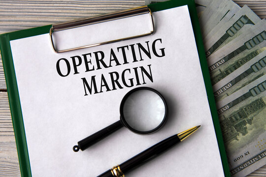 OPERATING MARGIN - words on a white sheet on the background of banknotes, magnifying glass and pen