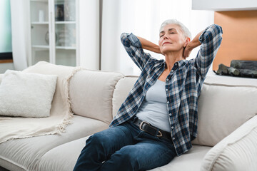 Chilling Caucasian middle-aged woman sitting on the sofa in the living room. Serene people concept....
