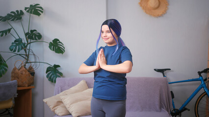 Young plus size latin hispanic teenager girl doing yoga at home. Cozy home interior with indoor...